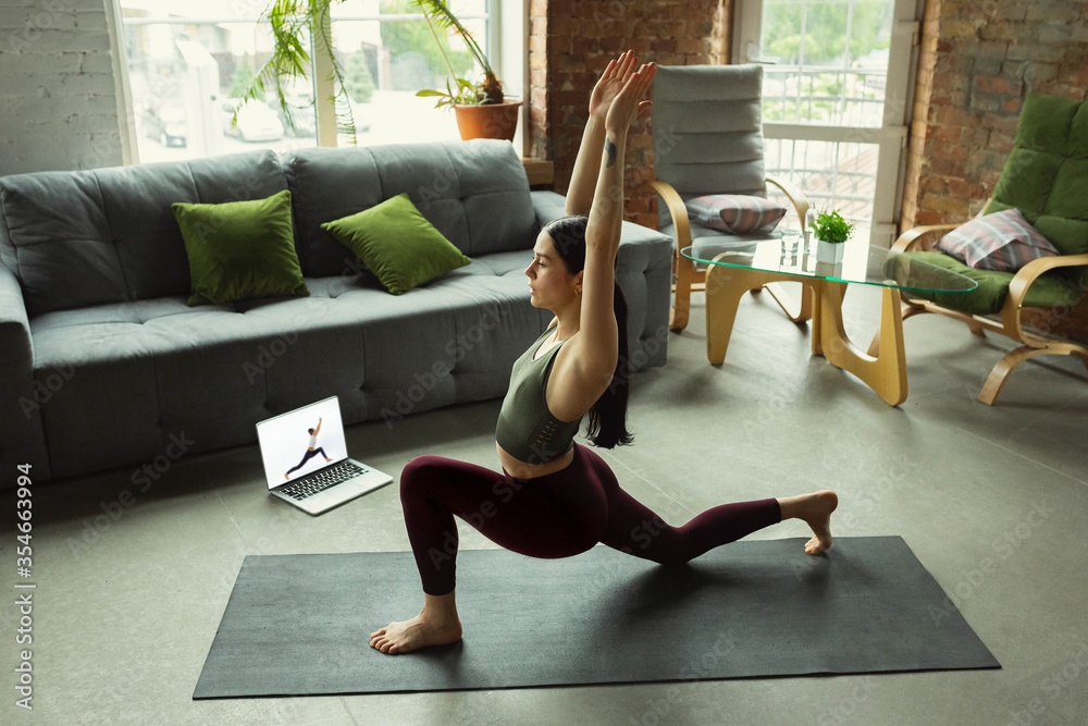 Asana. Sporty beautiful young woman taking professional yoga lessons online and practice at home. Concept of healthy lifestyle, wellness, wellbeing, looking for new hobby. Flexible and motivated.